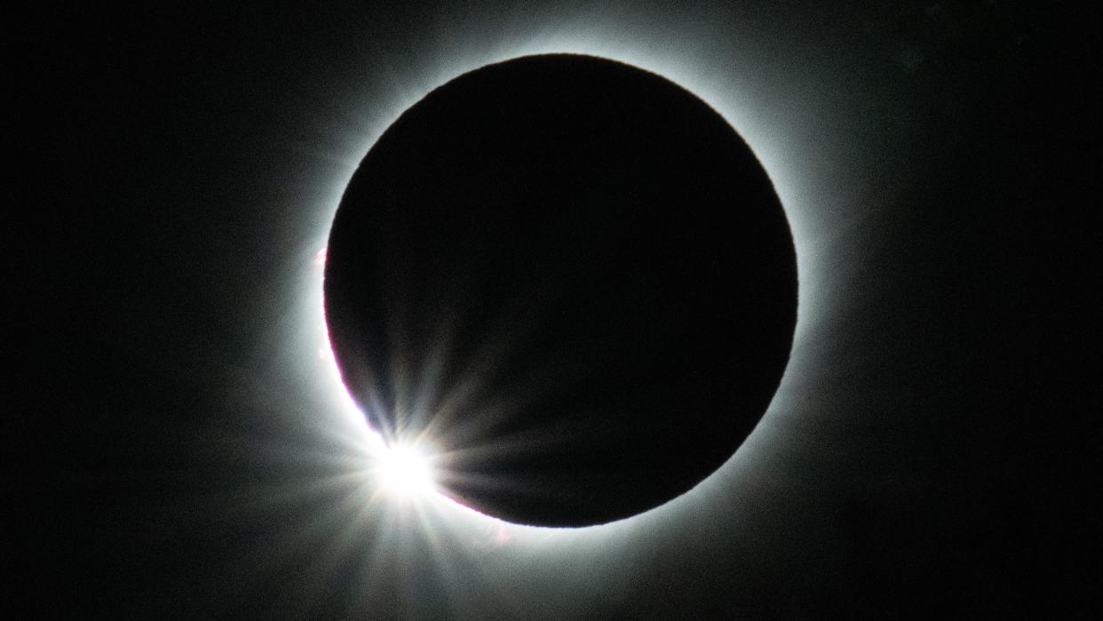  Total solar eclipse with a burst of sunlight emerging from behind the moon in the lower left corner. . 