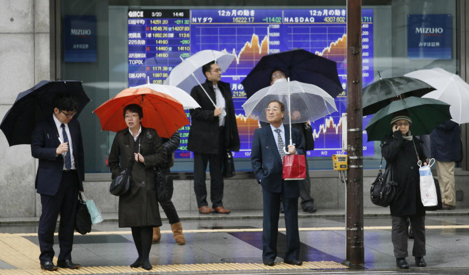 People stand in front of an electronic stock board of a securities firm in Tokyo, Thursday, March 20, 2014. Asian stocks inched down Thursday after comments from the new head of the Federal Reserve suggested U.S. interest rates could rise sooner than financial markets were anticipating. (AP Photo/Koji Sasahara)