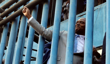 Former Congolese interior minister Emmanuel Ramazani Shadary waves to supporters through steel grills as he arrives to file his candidacy for the presidential election at the Congo's electoral commission (CENI) head offices at the Gombe Municipality in Kinshasa, Democratic Republic of Congo, August 8, 2018. REUTERS/Kenny Katombe/File Photo