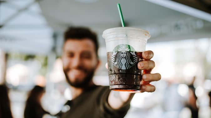 Millennial holding up a cup of Starbucks iced coffee