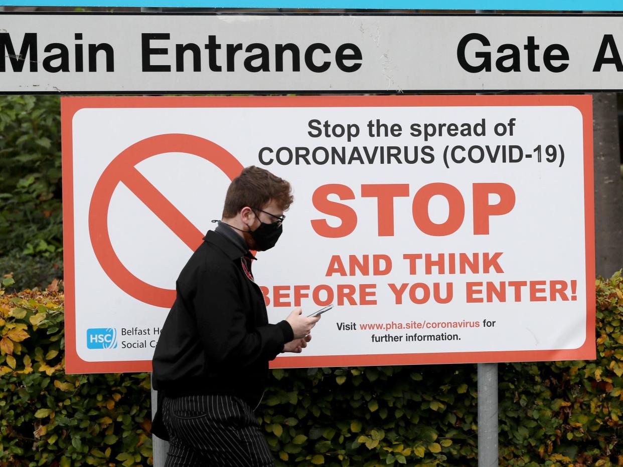 A man wearing a face mask walks past an entrance to Belfast City Hospital  (Brian Lawless/PA)