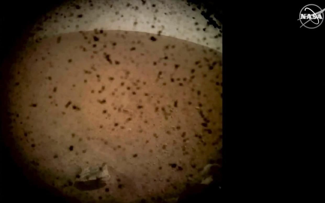 Debris is seen on the lens in the first image from NASA's InSight lander after it touched down on the surface of Mars - AFP