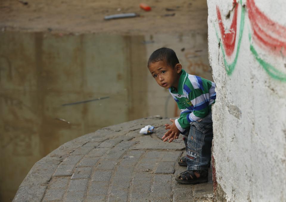 A Palestinian boy looks at a street flooded with sewage water from a sewage treatment facility in Gaza City November 14, 2013. Gaza municipality said they could not operate the sewage treatment facility due to shortages in fuel and power. Gaza's lone power plant shut its generators on November 1, 2013 due to a fuel shortage, a move that will likely increase already long blackout hours in the impoverished coastal territory run by the Islamist Hamas group. Power is provided to different areas in the territory in six-hour shifts since the closure. REUTERS/Mohammed Salem (GAZA - Tags: POLITICS ENVIRONMENT ENERGY)