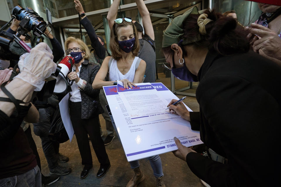 A woman holds a petition calling for an end to "Jew Hatred" as another woman signs her name to it during a protest outside the offices of New York Gov. Andrew Cuomo, Thursday, Oct. 15, 2020, in New York. Three Rockland County Jewish congregations are suing New York state and Gov. Andrew Cuomo, saying he engaged in a "streak of anti-Semitic discrimination" with a recent crackdown on religious gatherings to reduce the state's coronavirus infection rate. The suit was filed in Manhattan federal court on Wednesday. (AP Photo/Kathy Willens)