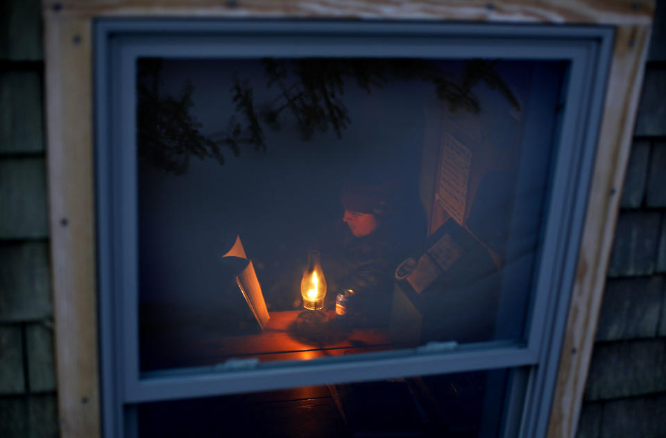 In this Wednesday, April 2, 2014 photo, caretaker J. P. Krol reads by the light of a kerosene lamp in the Gray Knob cabin in the Northern Presidential Range of the White Mountains in New Hampshire. Early in the week, the cabin sees few hikers but on weekends it often fills to its 15-person capacity. (AP Photo/Robert F. Bukaty)