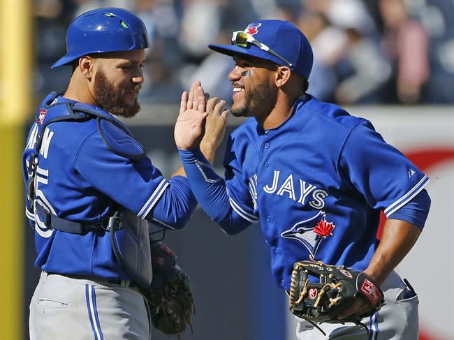 Toronto Blue Jays catcher Russell Martin, left, celebrates with second baseman Devon Travis after the Blue Jays defeated the New York Yankees 6-1 on an Opening Day that drew a record audience. (AP Photo/Kathy Willens)