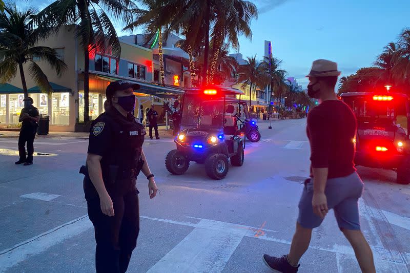 Police officers maintain the 8 pm curfew in Miami Beach