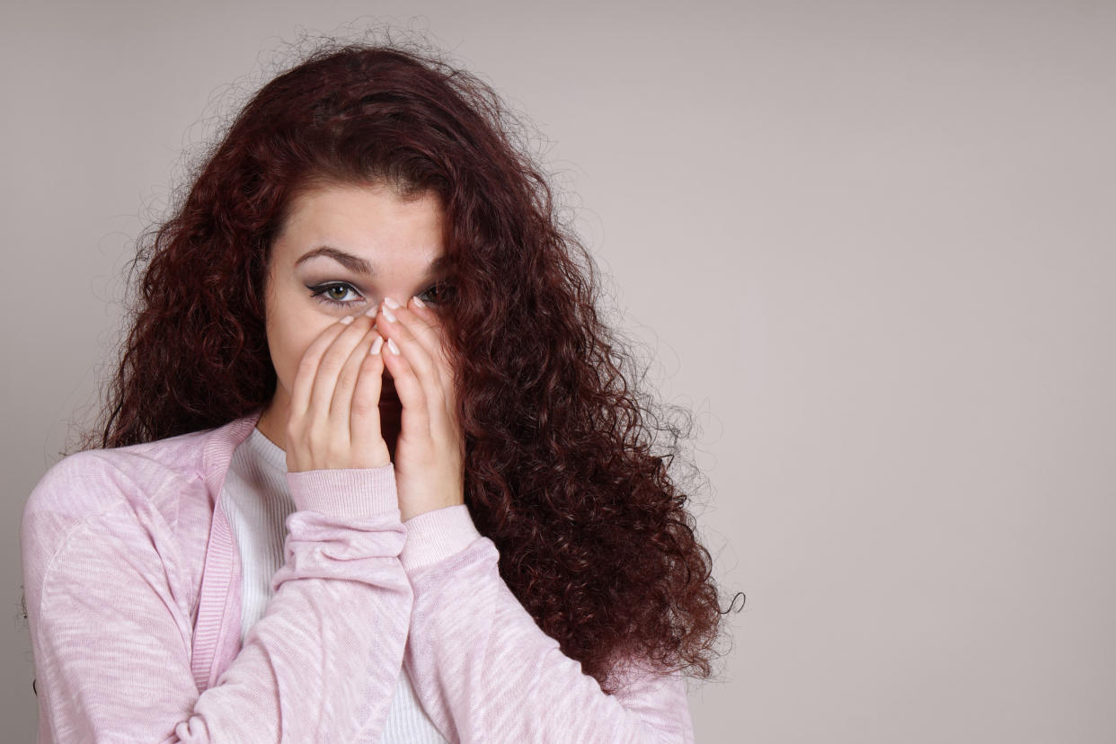 Portrait Of Young Woman Covering Face Against Beige Background