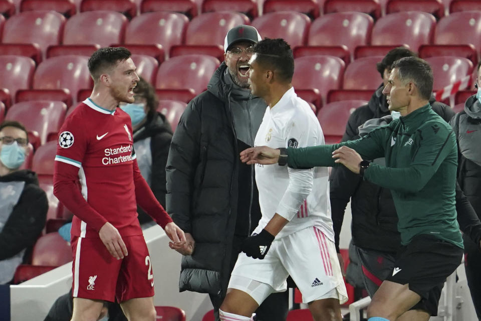 El técnico de Liverpool Jurgen Klopp, al fondo, grita en medio de una gresca entre Andrew Robertson (izquierda) y Casemiro del Real Madrid en el partido por los cuartos de final de la Liga de Campeones, el miércoles 14 de abril de 2021. (AP Foto/Jon Super)