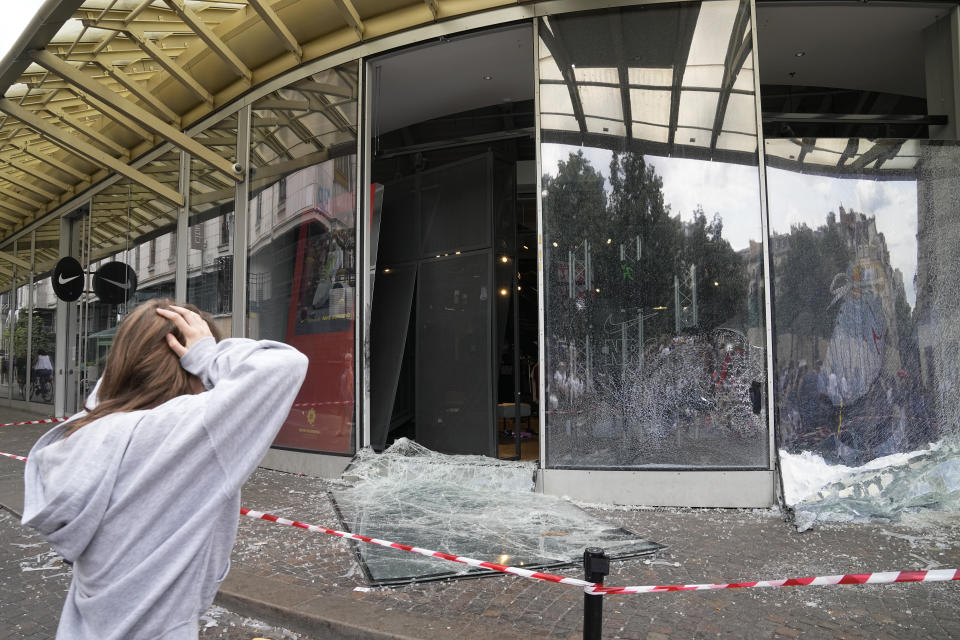 FILE - A woman reacts by damaged sports store after a third night of unrest, Friday, June 30, 2023 in Paris. In all, more than 3,600 people have been detained in the unrest across France since the death of Nahel on June 27, with an average age of 17, according to the Interior Ministry. The violence left more than 800 law enforcement officers injured, French courts are working overtime to process the arrests, including opening their doors through the weekend, with fast-track hearings around an hour long and same-day sentencing. (AP Photo/Michel Euler, File)
