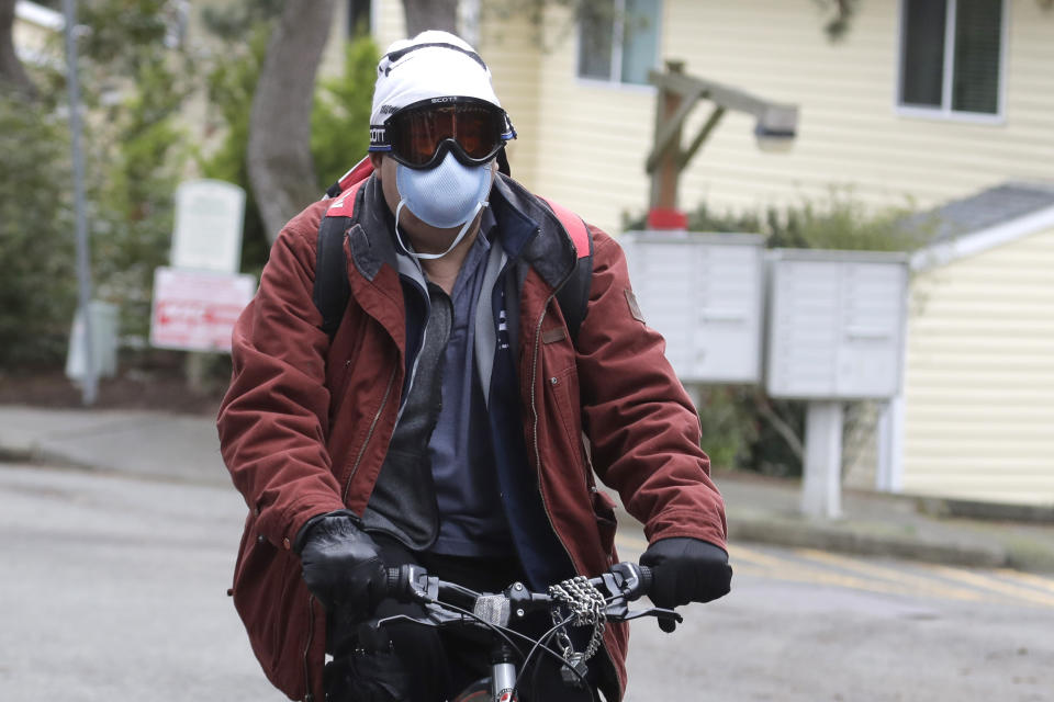 A man wearing a mask and goggles rides a bike