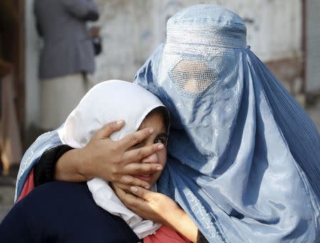 A woman holds her daughter's head as they walk away after a blast near the Pakistani consulate in Jalalabad, Afghanistan January 13, 2016. REUTERS/Parwiz