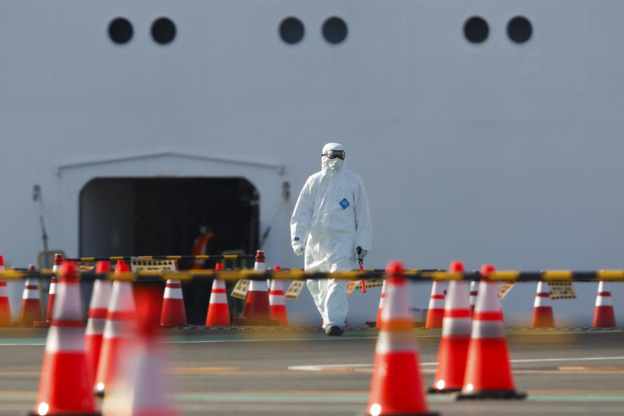 A health worker in a protective suit walks near the quarantined Diamond Princess cruise ship on Wednesday: AP