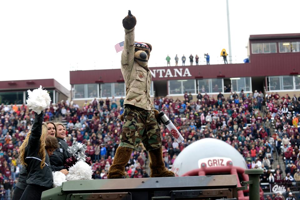 Montana mascot Monte entertains the crowd from the roof of a military vehicle being driven around Washington-Grizzly Stadium before the start an NCAA college football game, in Missoula, Montana.