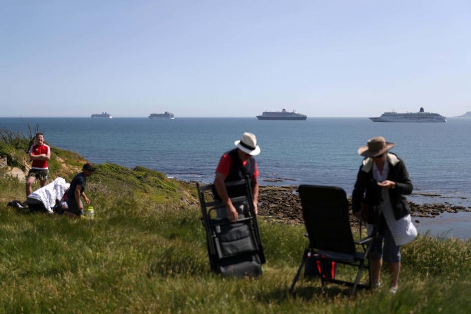 <p>Members of the public sit in the sunshine on the cliff overlooking The MV Britannia in Dorset</p>Getty Images