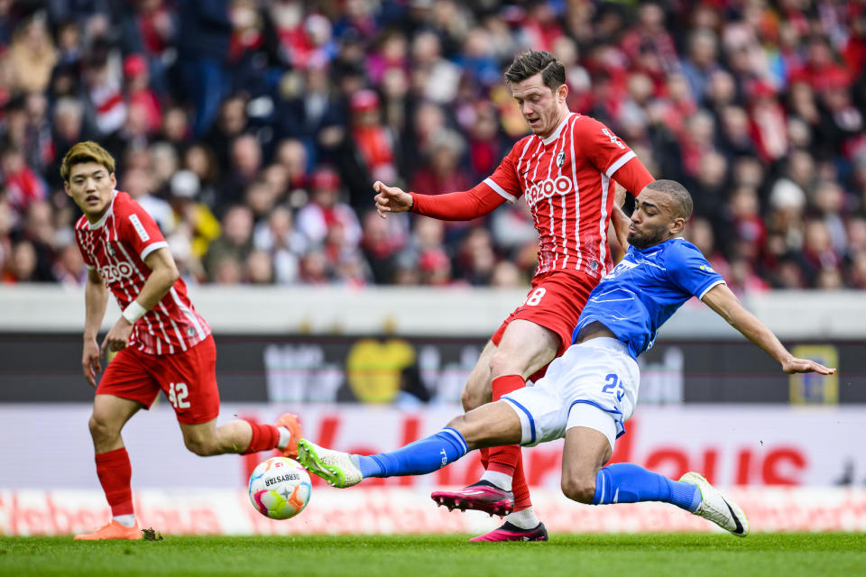 Freiburg's Michael Gregoritsch, center, in action against Hoffenheim's Kevin Akpoguma during the German Bundesliga soccer match between TSG 1899 Hoffenheim and SC Freiburg in Freiburg im Breisgau, Germany, Sunday March 12, 2023. (Tom Weller/dpa via AP)