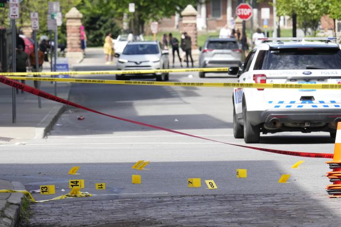 Markers indicate the location of shell casings Saturday at North High and East Russell streets in Columbus' Short North.