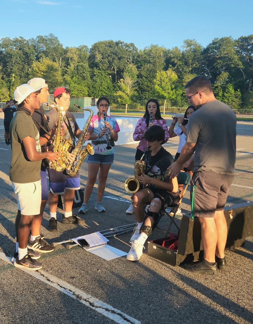 Dartmouth High School Marching Band's wind section practices in the parking lot Thursday with Winds Director Michael Rayner (far right).