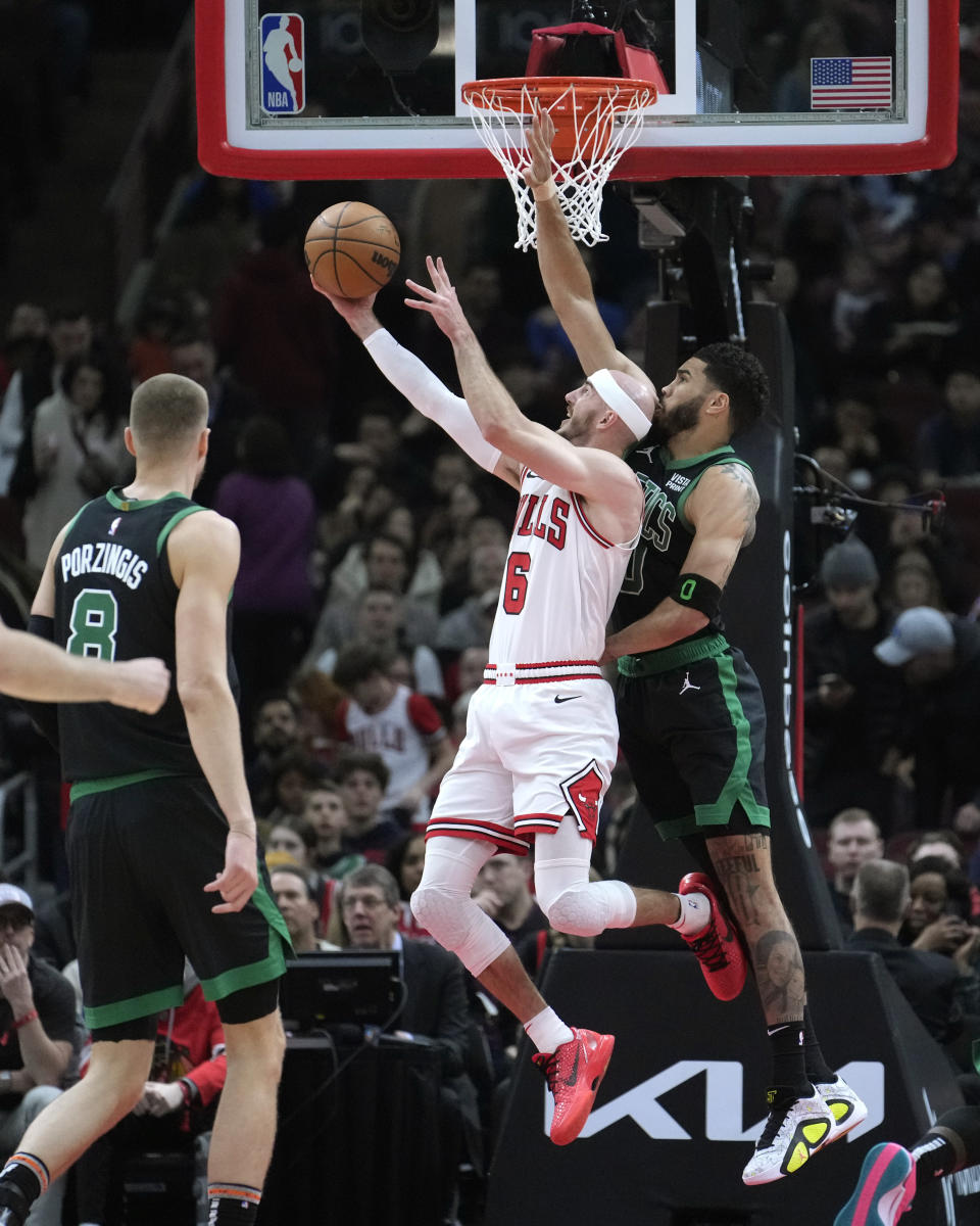 Chicago Bulls' Alex Caruso (6) shoots a reverse layup past Boston Celtics' Jayson Tatum, right, during the first half of an NBA basketball game Thursday, Feb. 22, 2024, in Chicago. (AP Photo/Charles Rex Arbogast)