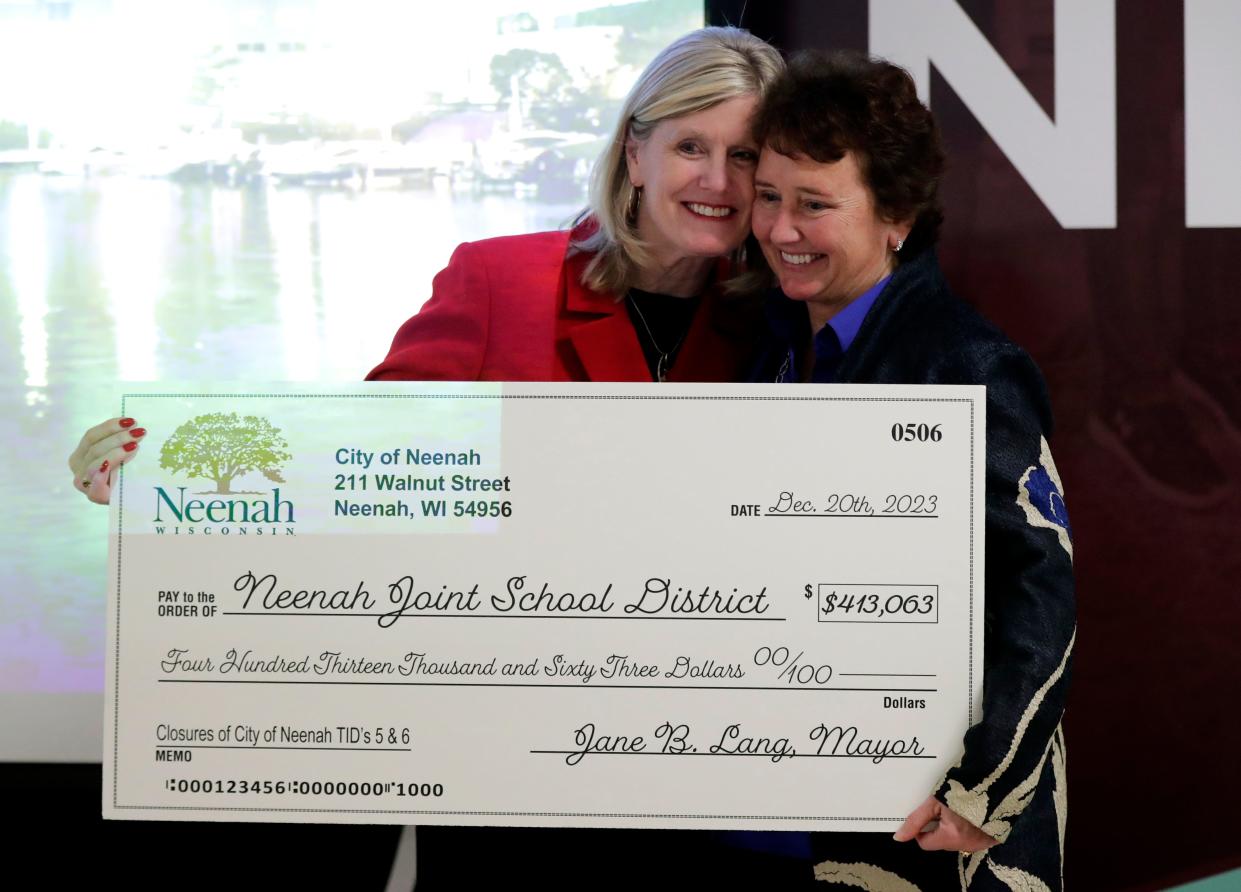 Superintendent Mary Pfeiffer, left, receives a $413,063 check for the Neenah Joint School District from Neenah Mayor Jane Lang during a press conference celebrating the successful closure of the city's tax incremental financing districts 5 and 6.