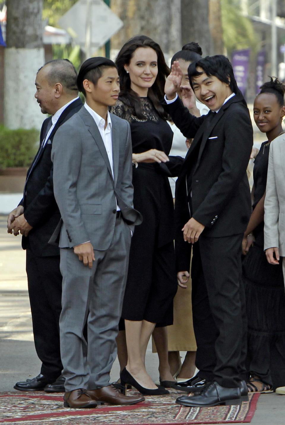 Hollywood actress Angelina Jolie, center, stands with her adopted children Pax, left, Maddox, waving second from right, Zahara, right, while they wait to meet Cambodia's King Norodom Sihamoni in Siem Reap province, Cambodia, Saturday, Feb. 18, 2017. Jolie on Saturday launch her two-day film screening of "First They Killed My Father" in the Angkor complex in Siem Reap province. (AP Photo/Heng Sinith)