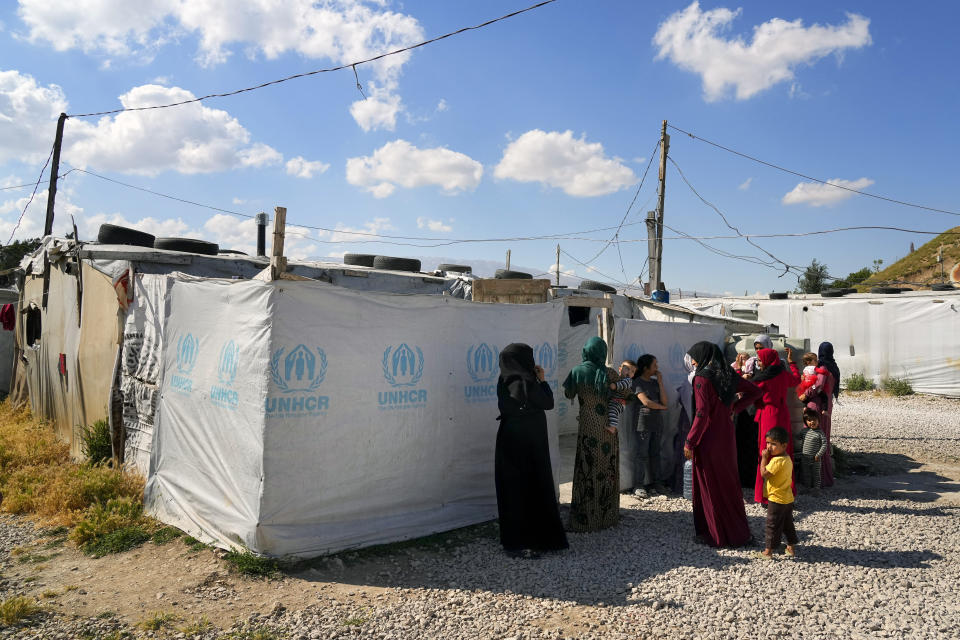 Syrian women and their children stand in front of their tents at a refugee camp in the town of Bar Elias, in Lebanon's Bekaa Valley, Tuesday, June 13, 2023. Aid agencies are yet again struggling to draw the world's attention back to Syria in a two-day donor conference hosted by the European Union in Brussels for humanitarian aid to Syrians that begins Wednesday. Funding from the conference also goes towards providing aid to some 5.7 million Syrian refugees living in neighboring countries, particularly Turkey, Lebanon and Jordan. (AP Photo/Bilal Hussein)