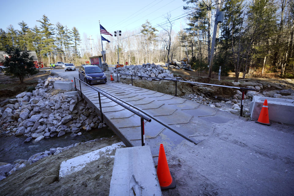 A vehicle travels over a temporary bridge that has been installed on a road to Sunday River ski resort's Grand Summit Hotel following this week's disastrous rainstorm, Thursday, Dec. 21, 2023, in Newry, Maine. The New England ski industry is working to recover before the Christmas vacation season. (AP Photo/Robert F. Bukaty)