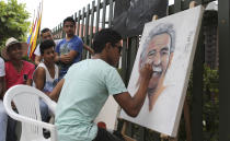 Friends surround Melquin Merchan, an 18-year-old painter from Aracataca, as he paints a portrait of Gabriel Garcia Marquez in front of the house where the Nobel laureate was born in Aracataca, Colombia, Friday, April 18, 2014. Garcia Marquez died at the age of 87 in Mexico City on Thursday. (AP Photo/Ricardo Mazalan)