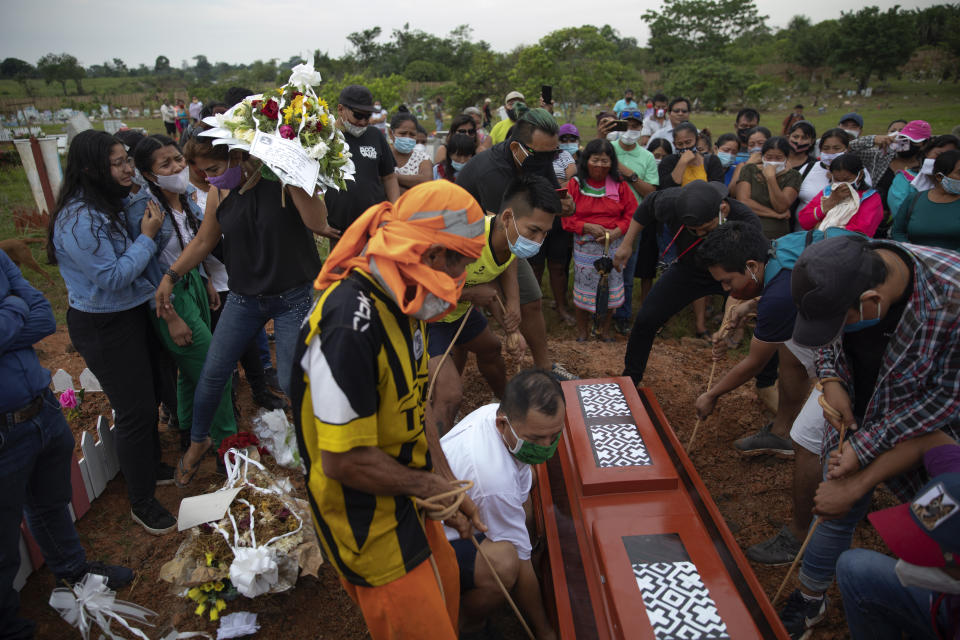 A coffin containing the remains of Jessica Soria Gonzáles, a 50-year-old Shipibo Amazonian indigenous artist who died due to complications related to COVID-19, is lowered into a freshly dug grave at her graveside ceremony in Pucallpa, in Peru's Ucayali region, Wednesday, Oct. 7, 2020. (AP Photo/Rodrigo Abd)