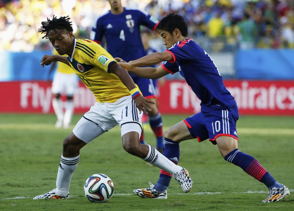 Colombia's Juan Cuadrado (L) fights for the ball with Japan's Shinji Kagawa during their 2014 World Cup Group C soccer match at the Pantanal arena in Cuiaba June 24, 2014. REUTERS/Jorge Silva (BRAZIL - Tags: SOCCER SPORT WORLD CUP)