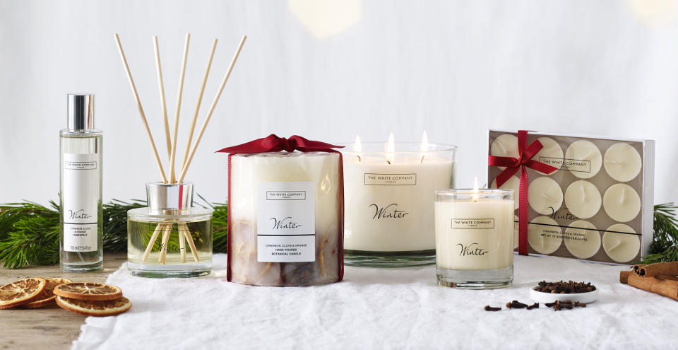Table with a white table cloth displaying Best-selling The White Company home scent Winter as a diffuser, large and small candles and room sprays