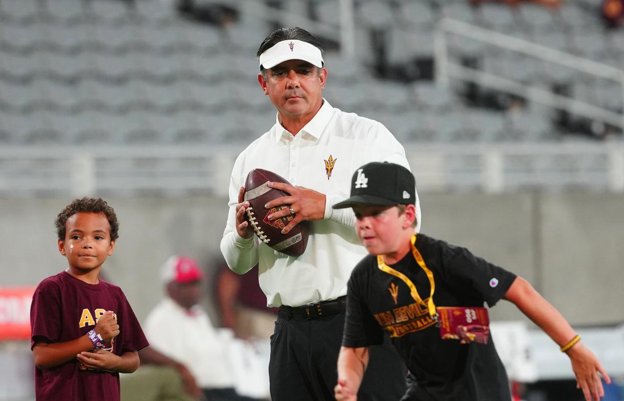 September 24, 2022; Tempe, Arizona; USA; ASU interim head coach Shaun Aguano throws passes to children on the field prior to a game at Sun Devil Stadium. Mandatory Credit: Patrick Breen-Arizona Republic