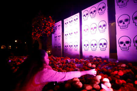 A woman puts a message on a floral offering for the victims who died in the September 19 earthquake as part of Day of the Dead celebrations at Mexico park in Mexico City, Mexico, November 1, 2017. REUTERS/Edgard Garrido
