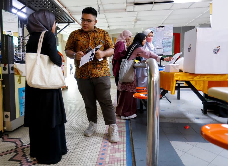 Zaim Mustaqim Marzuki explains to his fellow undergraduate the process of casting a vote for Malaysia's upcoming general election at Gombak