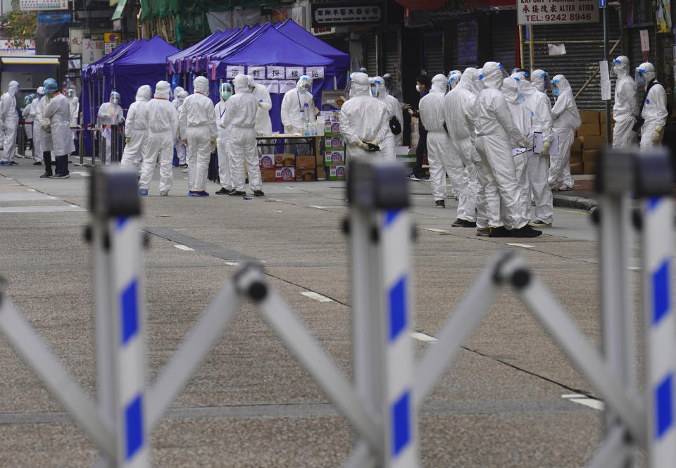 Government investigators wearing protective suits gather in the Yau Ma Tei area in Hong Kong, Saturday, Jan. 23, 2021. Thousands of Hong Kong residents were locked down Saturday in an unprecedented move to contain a worsening outbreak in the city, authorities said. (AP Photo/Vincent Yu)