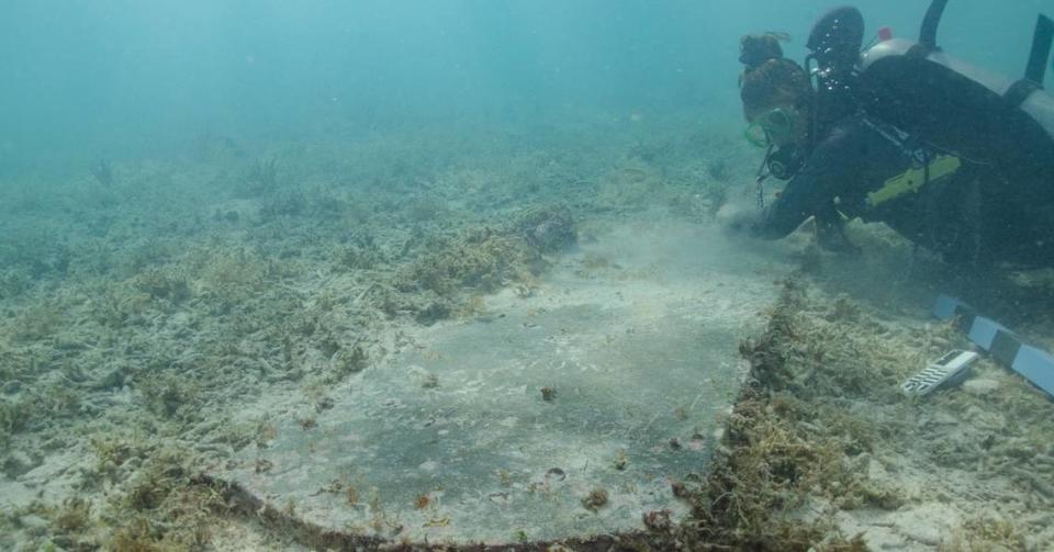 A diver uses a paper and pencil to take a rubbing of a headstone found underwater in the Dry Tortugas National Park.