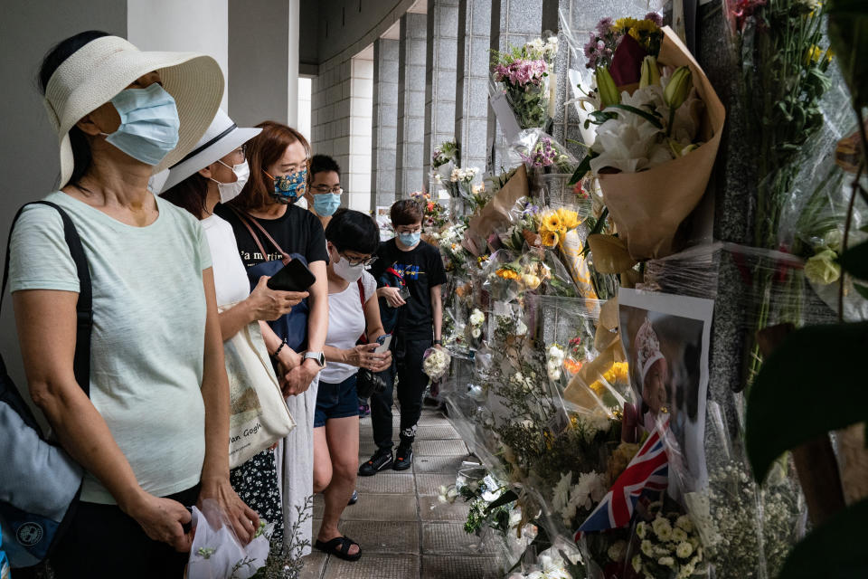 People wait in line to pay tribute to Queen Elizabeth II outside the British Consulate in Hong Kong, Friday, Sept. 16, 2022. In Britain, Thousands of mourners waited for hours Thursday in a line that stretched for almost 5 miles (8 kilometers) across London for the chance to spend a few minutes filing past Queen Elizabeth II's coffin while she lies in state. (AP Photo/Anthony Kwan)