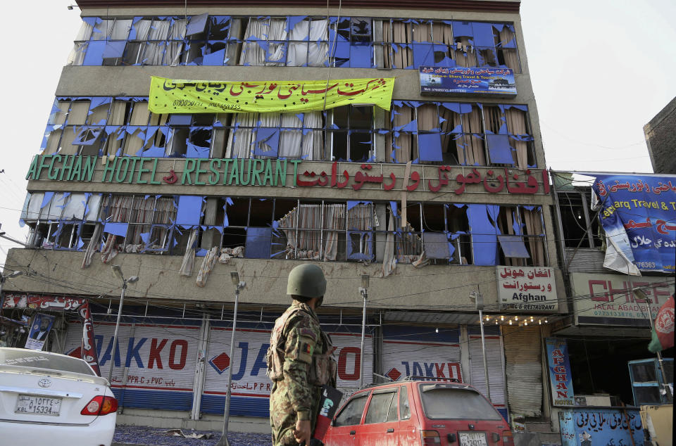 An Afghan army soldier stands next to a partly destroyed TV building which was hosting a television station after a multi-pronged attack on a police station in Jalalabad, the capital of eastern Nangarhar province, Afghanistan, Thursday, March 20, 2014. Taliban insurgents staged the attack, using a suicide bomber and gunmen to lay siege to the station, government officials said. Two remotely detonated bombs also exploded nearby. (AP Photo/Rahmat Gul)