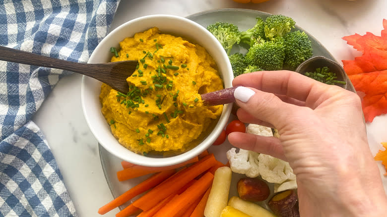 dipping carrot in hummus