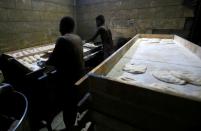 Workers prepare bread dough before baking in a traditional oven at a bakery in Khartoum