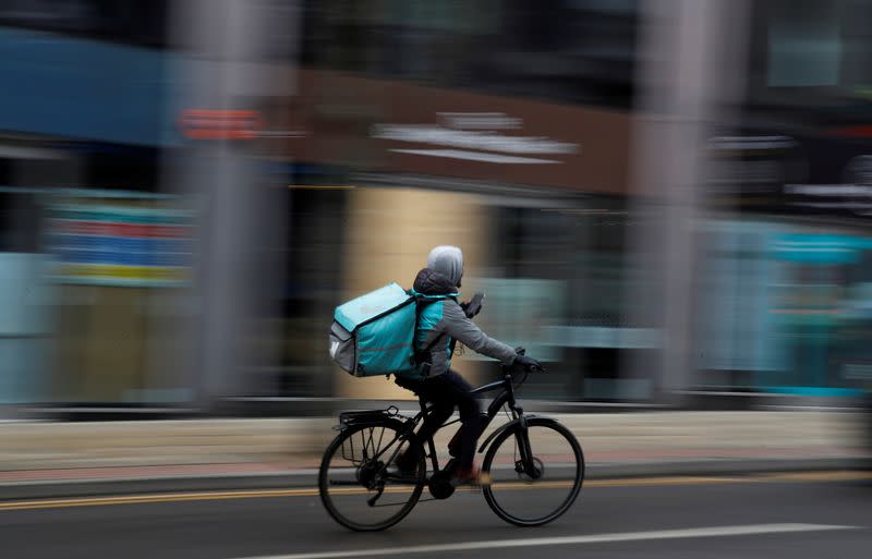 FILE PHOTO: A deliveroo delivery driver cycles through the centre of Manchester