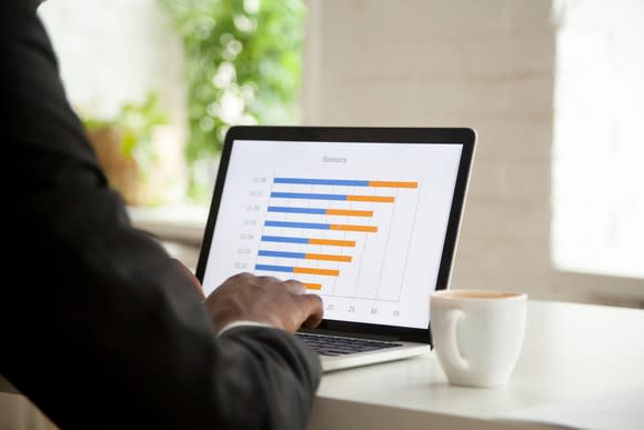 Man sitting a laptop with a bar graph on the screen