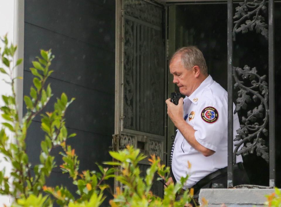 Chatham EMS Chief Chuck Kearns radios dispatch from the porch of a West Savannah home while a paramedic treats the patient inside.