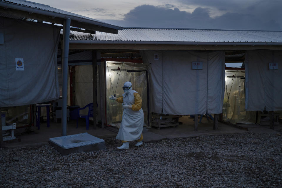 In this Saturday, July 13, 2019 photo, a health worker wearing a protective suit walks out of an isolation cube after visiting a patient at an Ebola treatment center in Beni, Congo. Health experts agree the experimental Ebola vaccine has saved multitudes in Congo. But after nearly a year and some 171,000 doses given, the epidemic shows few signs of waning. (AP Photo/Jerome Delay)