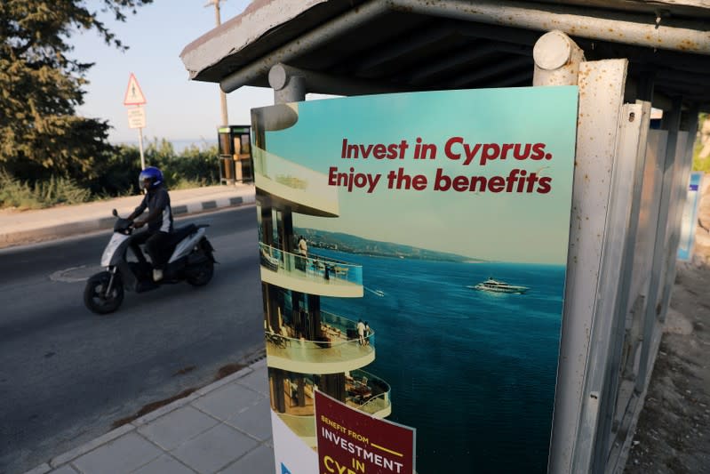 FILE PHOTO: A person riding a scooter passes an advertisement near Paphos, Cyprus