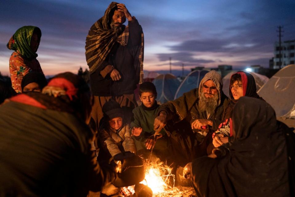 File photo: An Afghan family warms up next to a makeshift fire in Herat, Afghanistan, 29 November 2021 (AP)