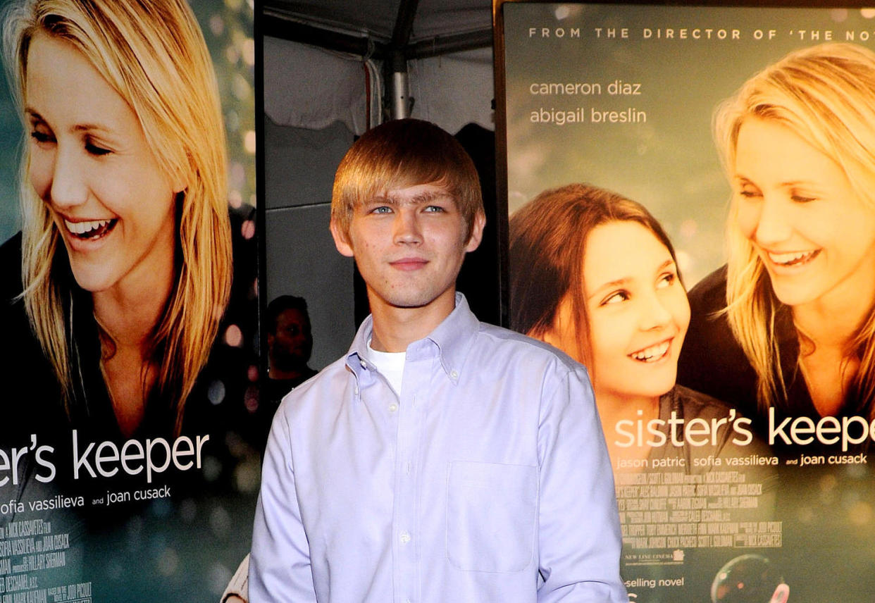 Evan Ellingson smiles infront of posters of 