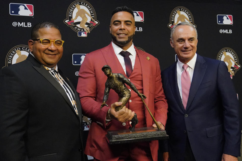 Robert D. Manfred, Jr., MLB Commissioner, right, Nelson Cruz, 2021 Roberto Clemente Award winner and Luis Roberto Clemente, Son of the late Hall of Famer Roberto Clemente pose before Game 2 of baseball's World Series between the Houston Astros and the Atlanta Braves Wednesday, Oct. 27, 2021, in Houston.(AP Photo/Sue Ogrocki)