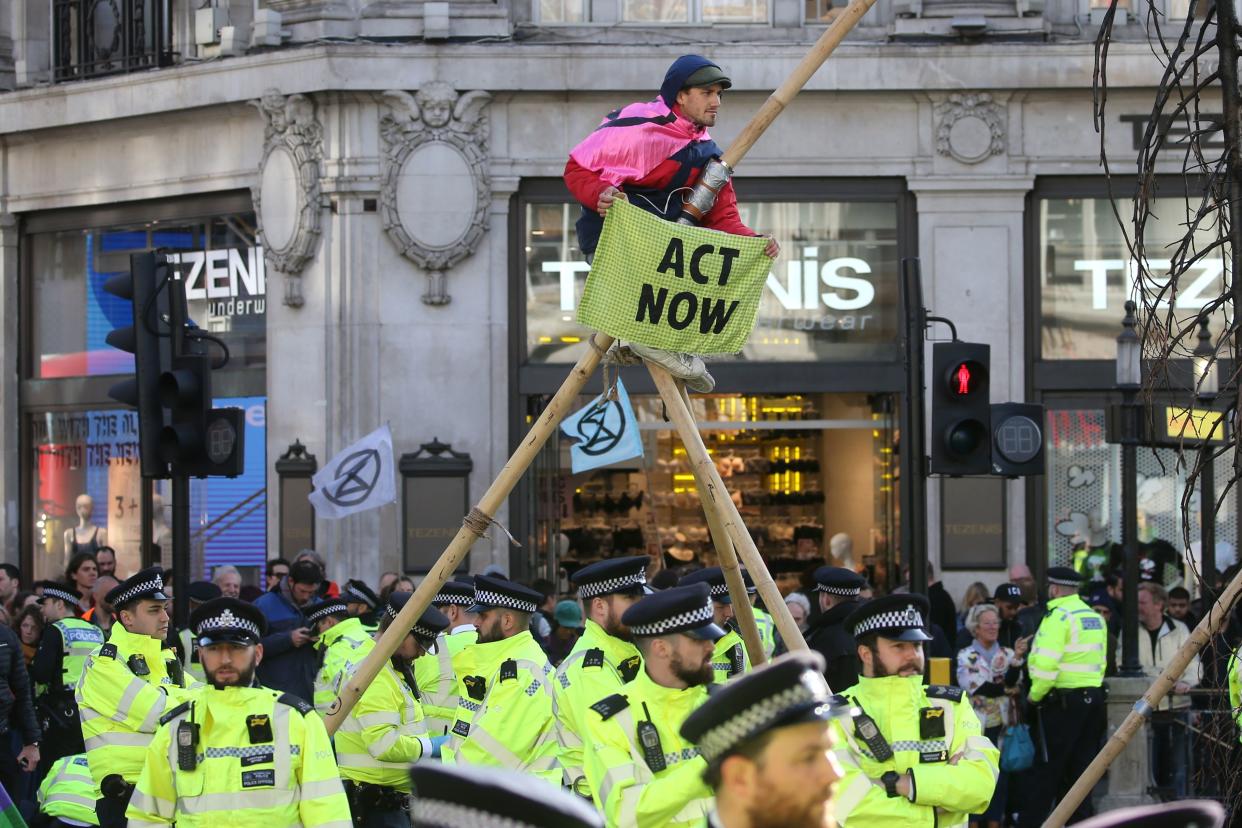 Police monitor as a climate activist perches on a make-shift structure in Oxford Street during the twelfth day of demonstrations by the climate change action group Extinction Rebellion, in London, on October 18, 2019. - The Extinction Rebellion pressure group has been staging 10 days of colourful but disruptive action across London and other global cities to draw attention to climate change. (Photo by ISABEL INFANTES / AFP) (Photo by ISABEL INFANTES/AFP via Getty Images)