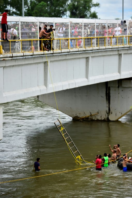 Honduran migrants, heading in a caravan to the US, help others get down to the Suchiate River from the Guatemala-Mexico international border bridge, in Ciudad Hidalgo, Chiapas state, Mexico